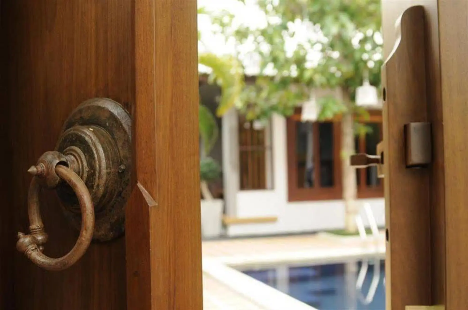 Wooden entrance gate of The Nest Samui, opening onto the pool courtyard